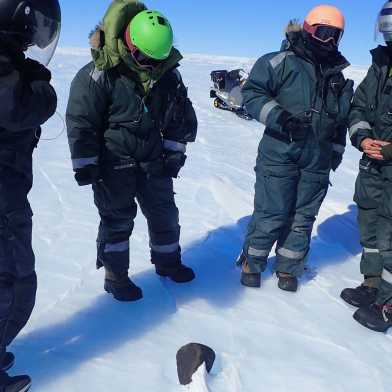 The expedition crew surrounding the newly found 7.6kg meteorite.